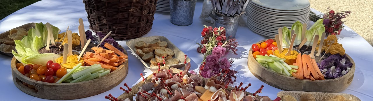 Plateaux apéritifs en bois : crudités, houmous, charcuterie, tomates cerises et pain.
