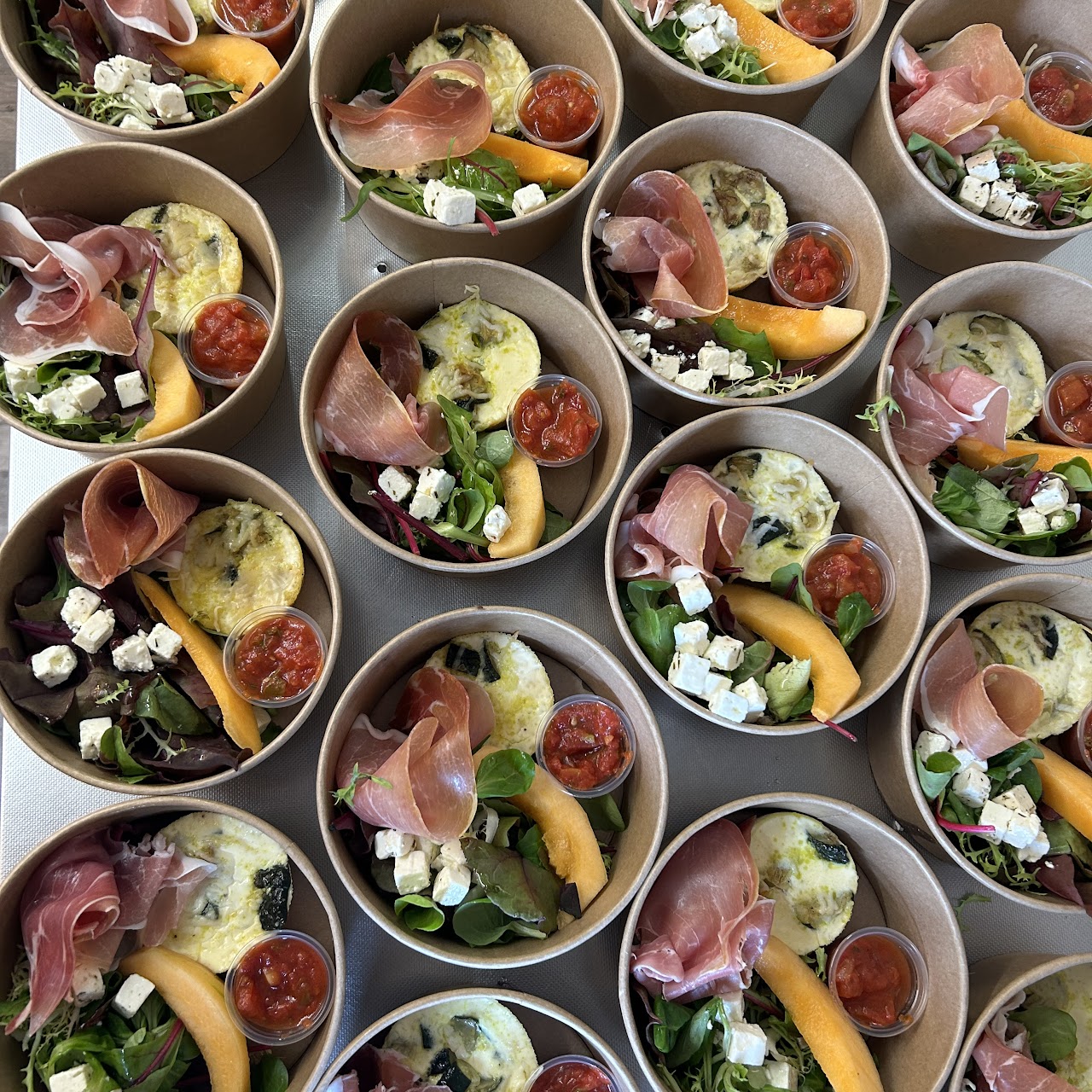 Portions individuelles en bols kraft : melon, feta, jambon cru, mesclun.